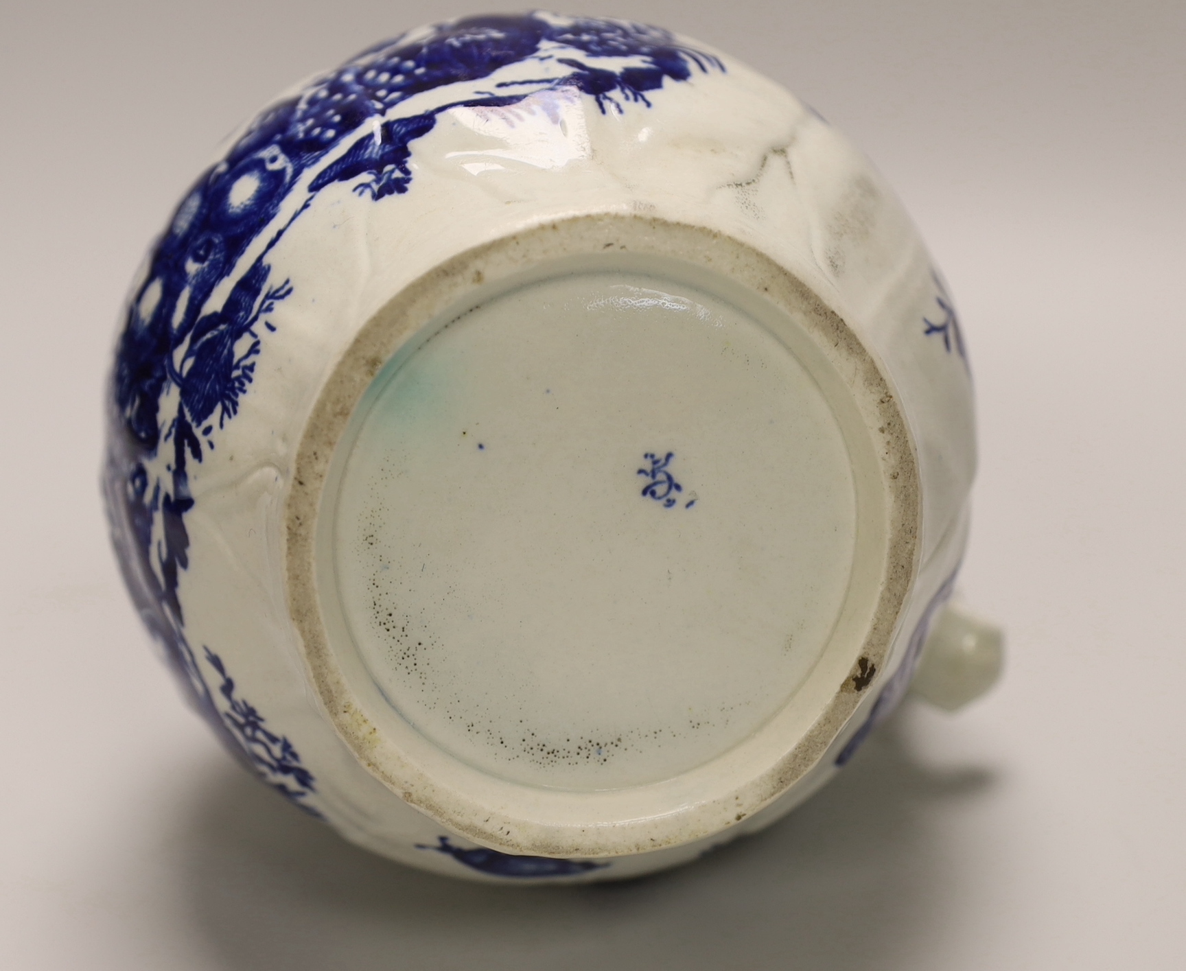 An 18th century Worcester fine mask jug decorated with the Parrot Pecking Fruit pattern, disguised numeral mark, 21cms high